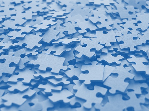 A heap of disintegrated puzzle pieces in chaos to be put together. Blue tone.