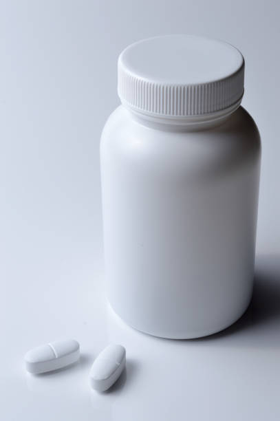 istock white plastic medicine jar and two white pills. light background. 1398986017