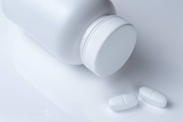istock white plastic medicine jar and two white pills. light background. 1398986060