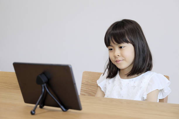 istock Japanese girl watching video on tablet PC (7 years old) 1398986135
