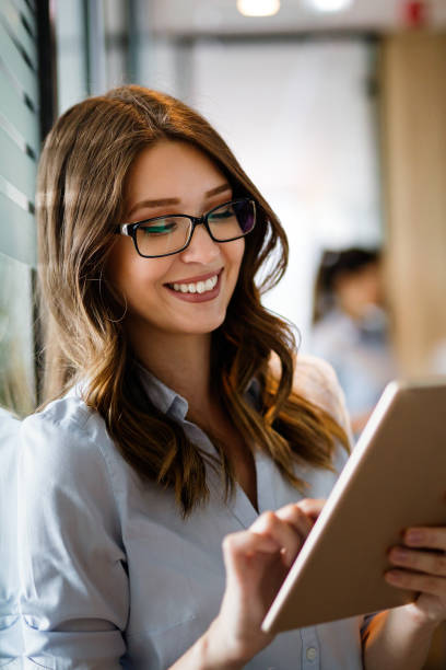 istock Attractive young businesswoman using a digital tablet while standing in front of windows in office 1398986734