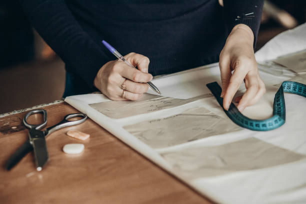 istock Tailor sews clothes. A woman dressmaker makes patterns in her atelier 1398987518