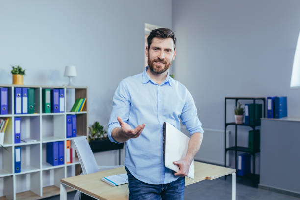 porträt eines erfolgreichen büroangestellten, mann, der in die kamera schaut und lächelt, der in einem modernen büro arbeitet - darstellung stock-fotos und bilder