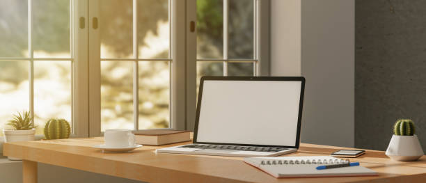 istock Home workspace with laptop computer blank screen mockup, coffee mug, decor plant, and accessories on tabletop in the modern bright living room. 3d rendering 1398988955