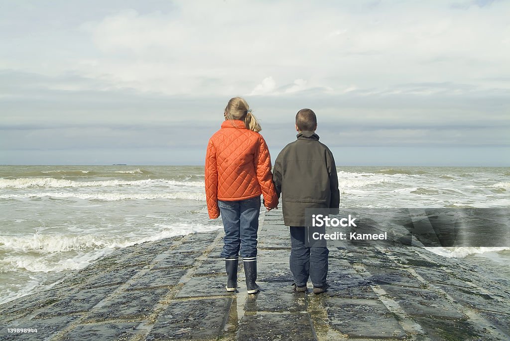 Hermano y hermana en un rompeolas, con vista al mar - Foto de stock de Actividad libre de derechos