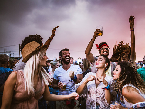 Young cheerful people having fun while dancing together at the outdoor party.