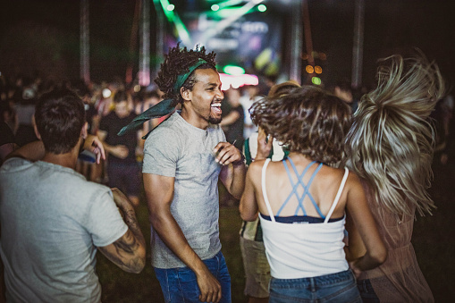 Group of happy friends having fun while dancing on music festival at night.