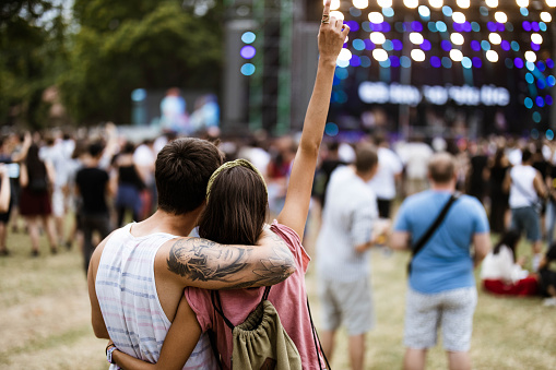 Rear view of a loving couple embracing while enjoying in music concert.