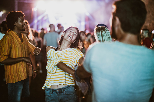 Carefree couple having fun while dancing on music festival by night.