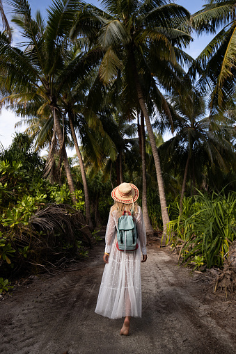 Rear view of a female tourist walking through nature in summer day.