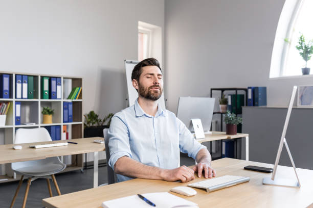 istock Businessman in the office with closed eyes performs breathing exercises, freelancer working on the computer 1398991153