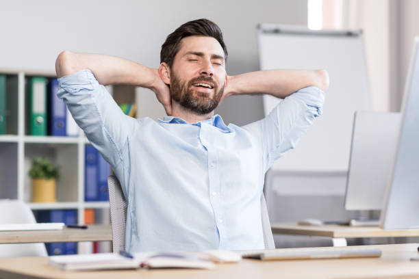 istock Young handsome man, office worker, sitting at a computer desk, stretching, tired, taking a break, doing yoga exercises, resting 1398991162