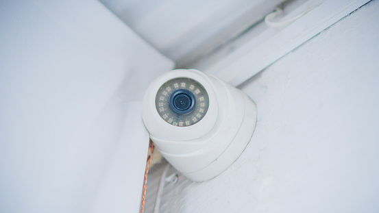 indoor security camera on a white wall under the ceiling