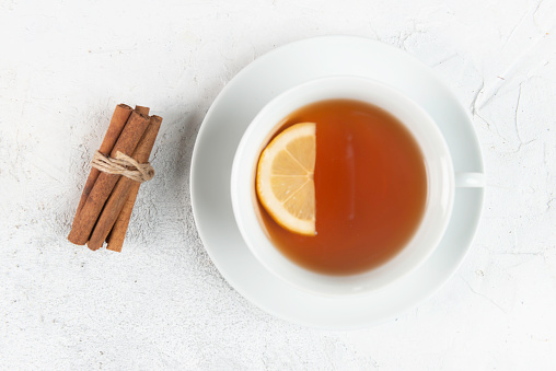 Directly above view of cinnamon sticks and a tea cup with herbal tea and a slice of lemon in it.