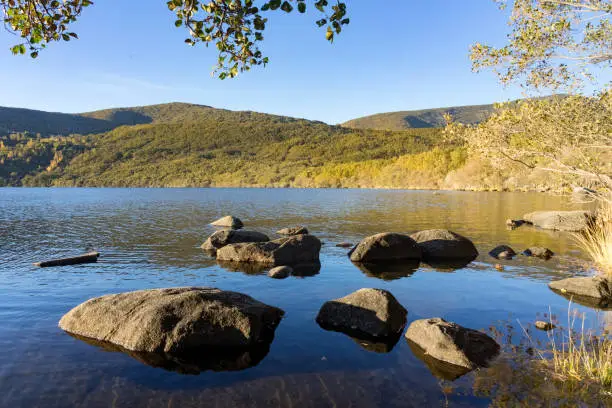 Photo of Sanabria Lake Natural Park in autumn at sunset with the mountains reflected in the water, Zamora, Castilla y León, Spain.