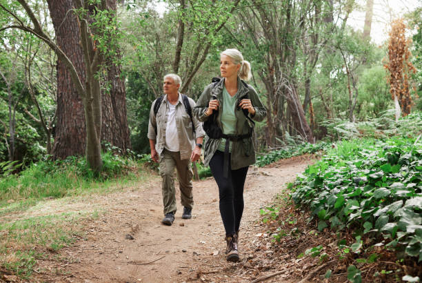 un couple caucasien mature en randonnée ensemble. homme et femme âgés souriant et marchant dans une forêt dans la nature - tourist senior adult senior couple couple photos et images de collection