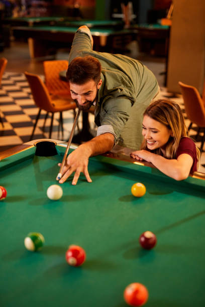 istock Young happy couple enjoying playing billiard on a date in pool hall 1398993336
