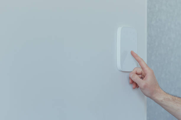 istock Businessman enters finger password lock code on alarm panel, on white wall, rear view of man with beard 1398993493