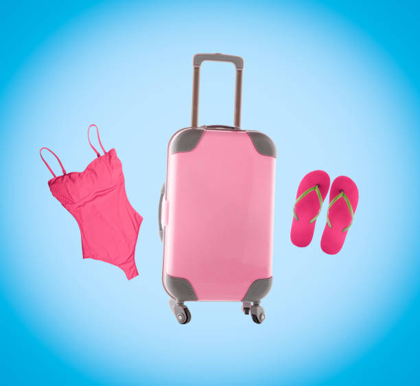 Summer collage with pink luggage, flip flops and swimsuit on blue background.