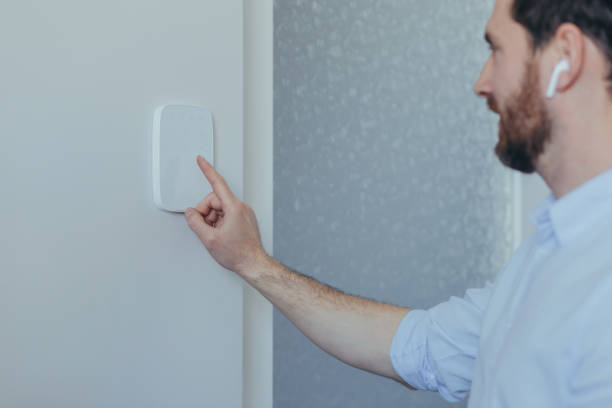istock Businessman enters finger password lock code on alarm panel, on white wall, rear view of man with beard 1398993513