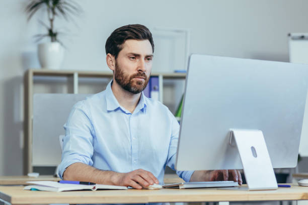 istock Thinking business man, working in a modern office during the day, sitting at a table, working with a computer, thinking about solving a business contract 1398993530