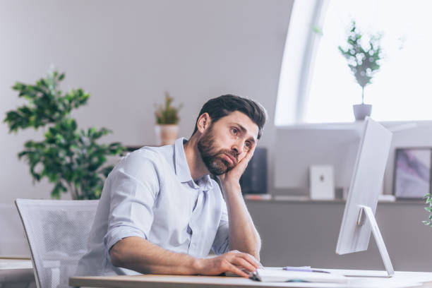 istock Tired and thoughtful office worker. Sitting at a desk in the office, at the computer, holding his head in his hands, tired, in a white shirt 1398993604