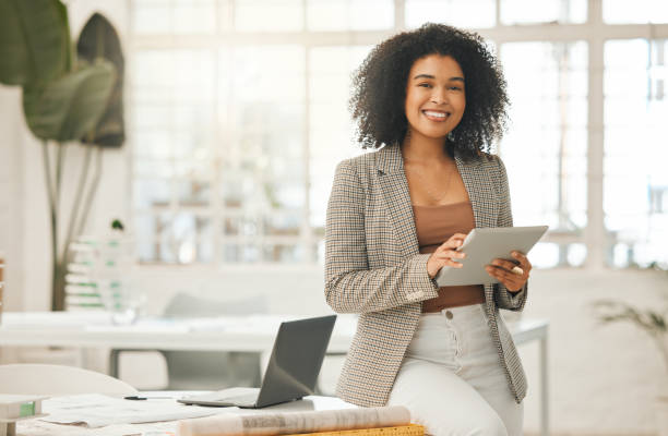 femme d’affaires heureuse utilisant une tablette numérique. jeune femme d’affaires de premier plan utilisant une tablette sans fil. designer créative travaillant dans son agence. designer debout dans son bureau à l’aide d’une application en lign - female photos et images de collection