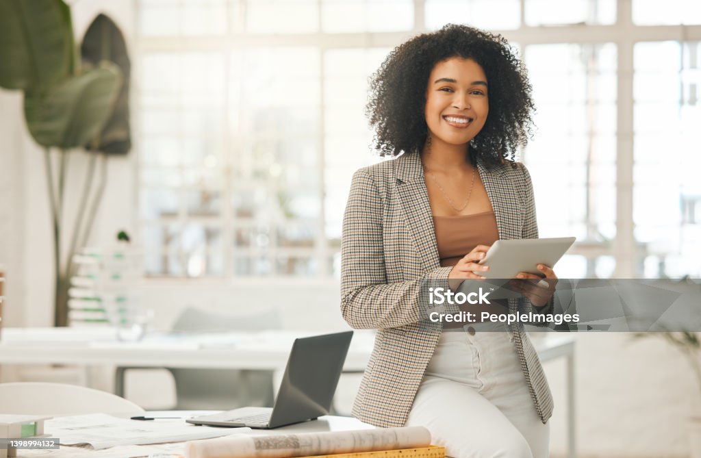 Happy businesswoman using a digital tablet. Young leading businesswoman using a wireless tablet. Creative designer working in her agency. Designer standing in her office using an online app Women Stock Photo