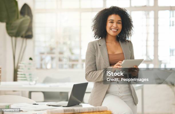 Happy Businesswoman Using A Digital Tablet Young Leading Businesswoman Using A Wireless Tablet Creative Designer Working In Her Agency Designer Standing In Her Office Using An Online App Stock Photo - Download Image Now