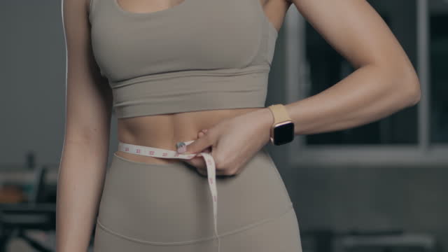 A young Asian woman is wearing a bra and leggings to measure waist circumference after exercise. weight loss through exercise