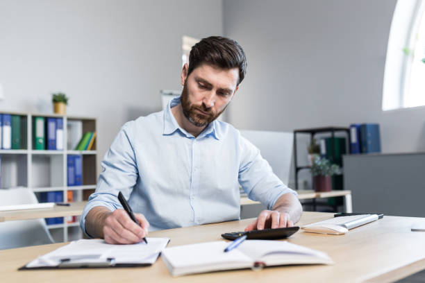 istock Thinking businessman working with documents in the office, man reviewing financial reports 1398995443