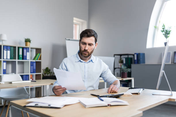 istock Thinking businessman working with documents in the office, man reviewing financial reports 1398995488