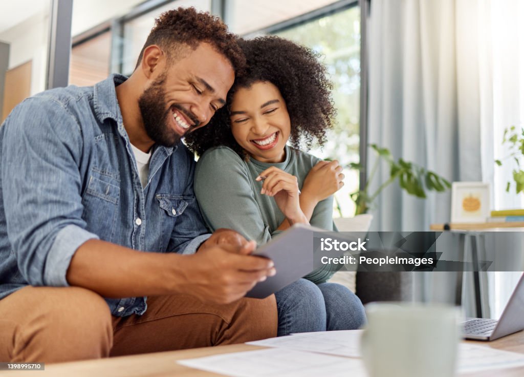 Young happy mixed race couple going through documents and using a digital tablet at a table together at home. Cheerful hispanic husband and wife smiling while planning and paying bills. Boyfriend and girlfriend working on their budget Savings Stock Photo