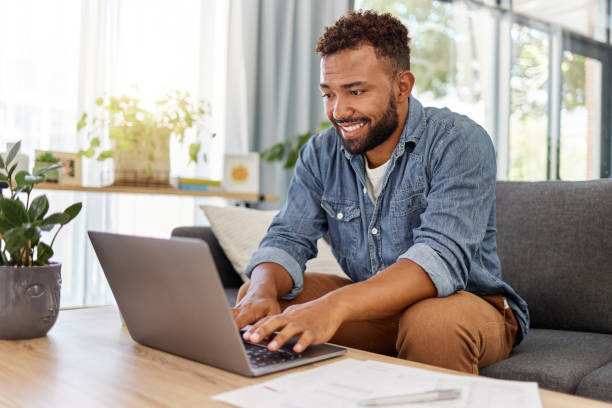 istock Young mixed race man working on filling out forms while typing on a laptop at home. One hispanic man planning and sending an email alone in the lounge at home 1398995797