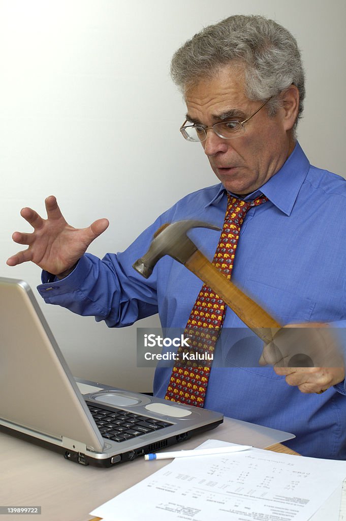 Fury A businessman, fed up with his laptop crashing, goes berserk and takes a hammer to it. Anger Stock Photo