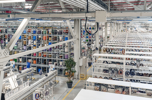 Interior of modern warehouse with coils of colored cable on metal shelves. Car wiring plant. Panoramic view.