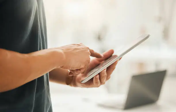 Photo of Closeup of a businessman using a digital tablet. Hands of architect working online on a wireless device. Hands of businessman scrolling online apps on a tablet. Startup designer using his device