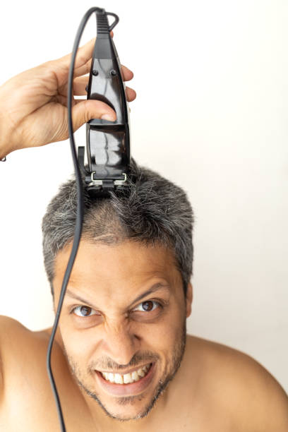 istock Handsome gray-haired man is cutting hair himself. 1398999427