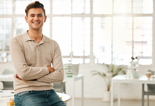 Proud businessman sitting on his desk. Confident businessman in his office. Young architect in his design office. Creative entrepreneur working in his office. Portrait of happy businessman