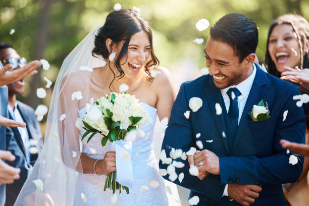 les invités jettent des confettis sur les mariés alors qu’ils passent après leur cérémonie de mariage. jeune couple joyeux célébrant le jour de leur mariage - wedding photos et images de collection