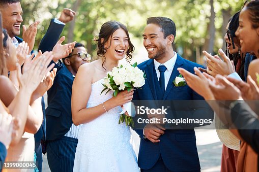 istock Wedding guests clapping hands as the newlywed couple walk down the aisle. Joyful bride and groom walking arm in arm after their wedding ceremony 1399000045