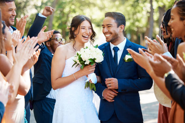 wedding guests clapping hands as the newlywed couple walk down the aisle. joyful bride and groom walking arm in arm after their wedding ceremony - wedding behavior horizontal men imagens e fotografias de stock