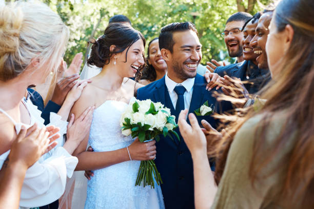istock Happy bride and groom standing together while greeting guests after their wedding ceremony. Newlyweds smiling while friends and family congratulate them on their marriage 1399000088