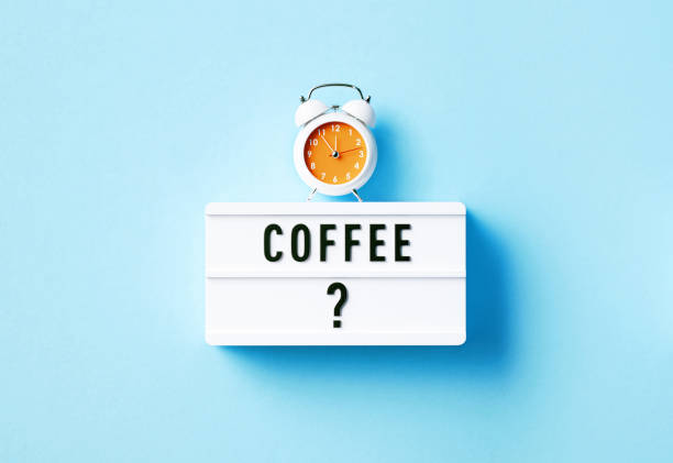 Alarm clock and coffee written white lightbox sitting on blue background. Horizontal composition with copy space.
