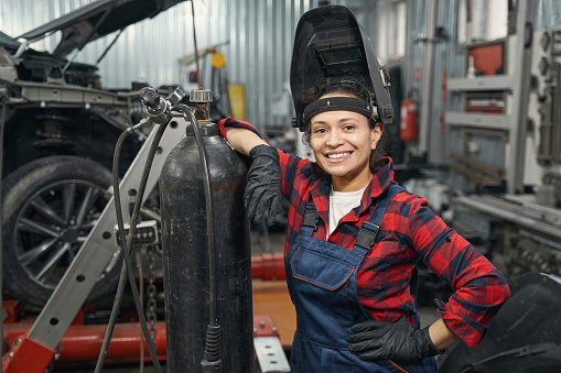 Alegre mujer mecánica automotriz de pie en el taller de reparación de vehículos photo