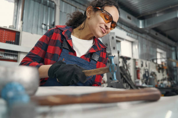 istock Female auto mechanic using hammer in automobile garage 1399002919