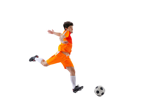 Leg kick. Professional football, soccer player in motion isolated on white studio background. Concept of sport, match, ad, active lifestyle, goal and hobby. Sportsmen wearing bright orange football kit.