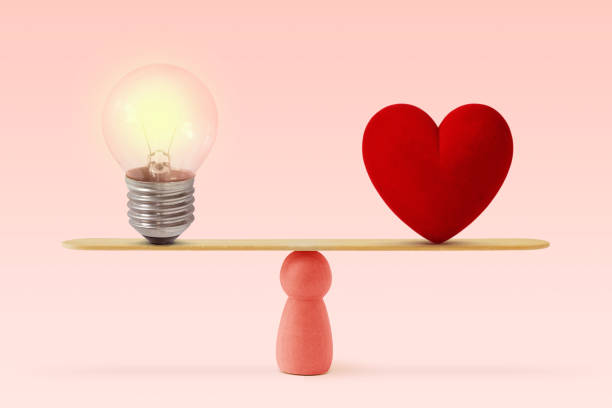Light bulb and heart on scale on pink background- Concept of woman and balance between heart and brain stock photo