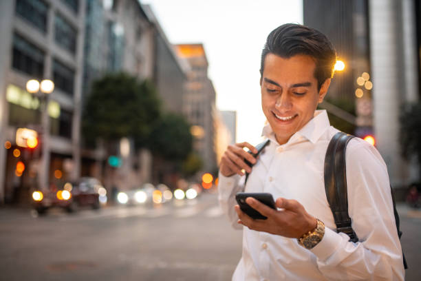 maschio ispanico sorridente alla fine degli anni '20 che controlla il suo smartphone - determination 20s adult attractive male foto e immagini stock