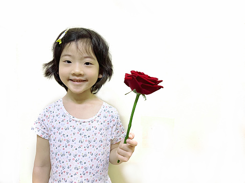 Portrait of smiling cute girl in casuals pointing while standing against gray background